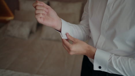 Man-in-a-white-shirt-fastening-his-cufflinks,-preparing-for-a-formal-event