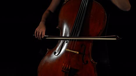 closeup of female hands playing cello, black moody background