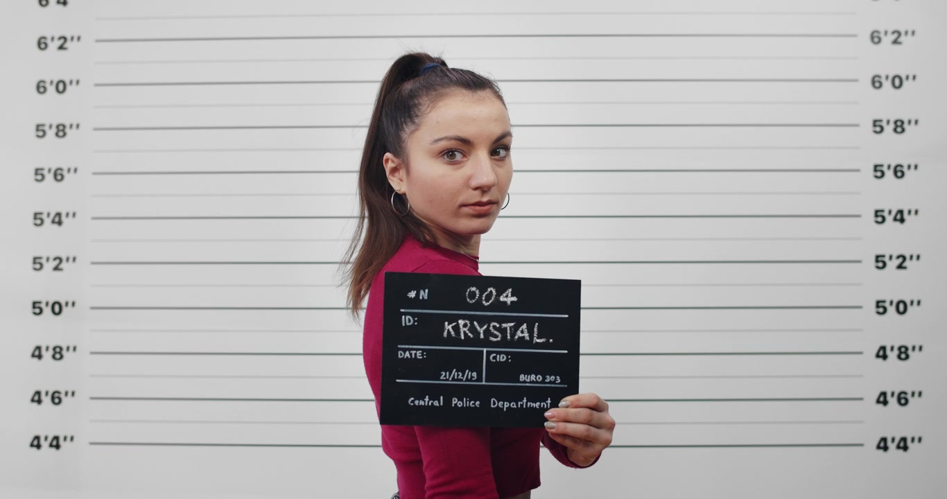 Mladá žena pózující pro policejní identifikační fotografii