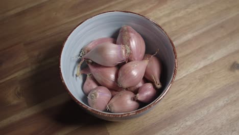 medium close shot of fresh shallots lying in a ceramic bowl