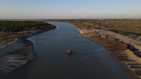 bulldozer carries sand to shore through water