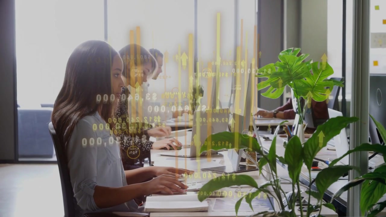 Vertical video: Foreground woman writing while camera pulling back yellow bars showing office KPIs