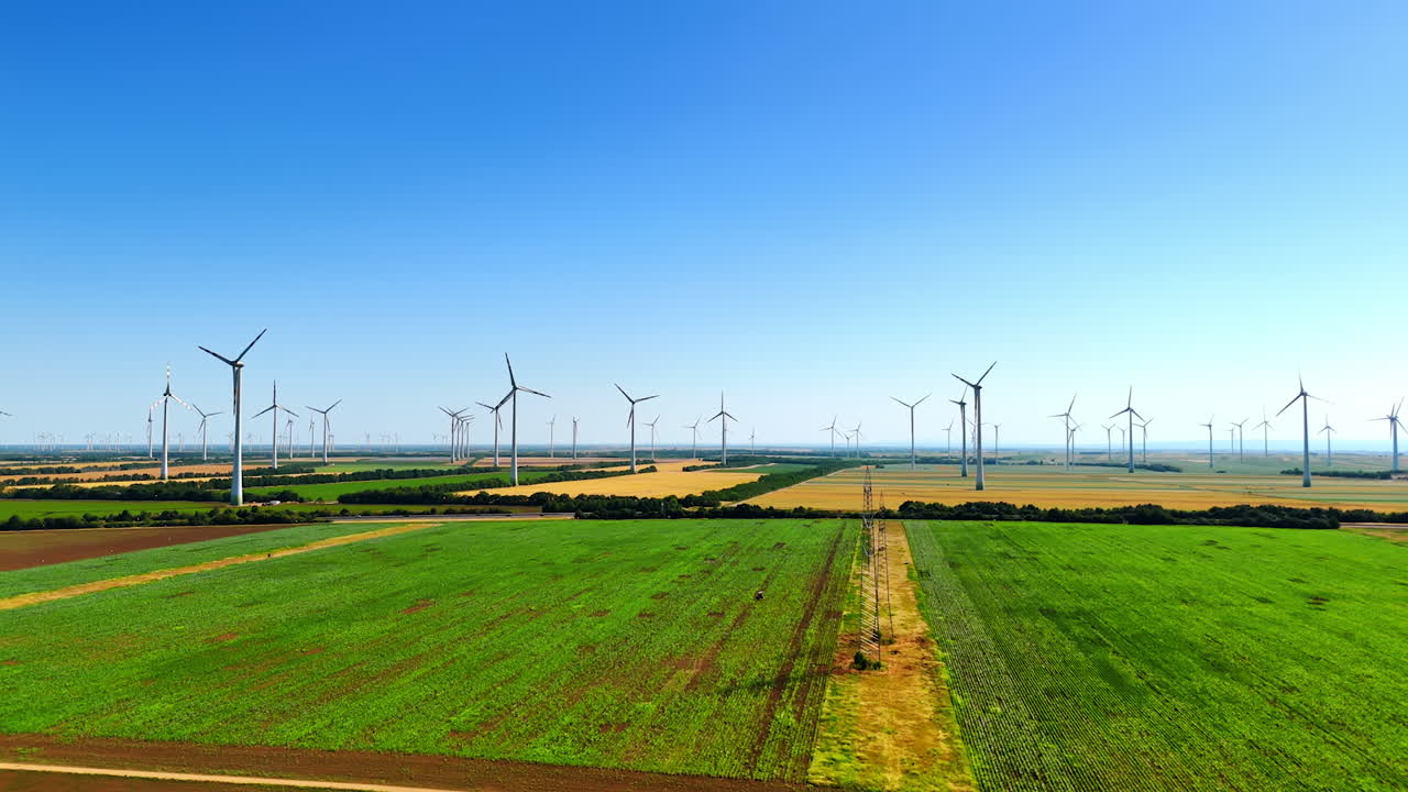 Multiple powerful wind mills rotate in the wind in the countryside. Wind farms produce green energy. Aerial view