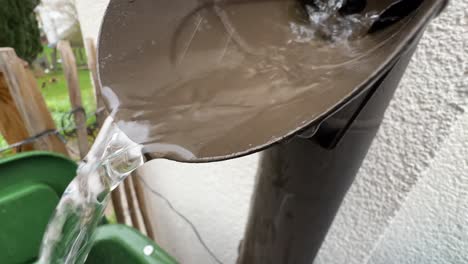 Extreme-close-up-shot-of-water-flowing-out-of-a-typical-german-drain-pipe-during-rain