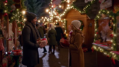 a couple exchanging christmas gifts at a festive night market