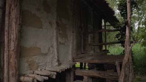 Old-wooden-cabin-with-a-thatched-roof-surrounded-by-lush-greenery,-evoking-a-rustic-and-tranquil-mood