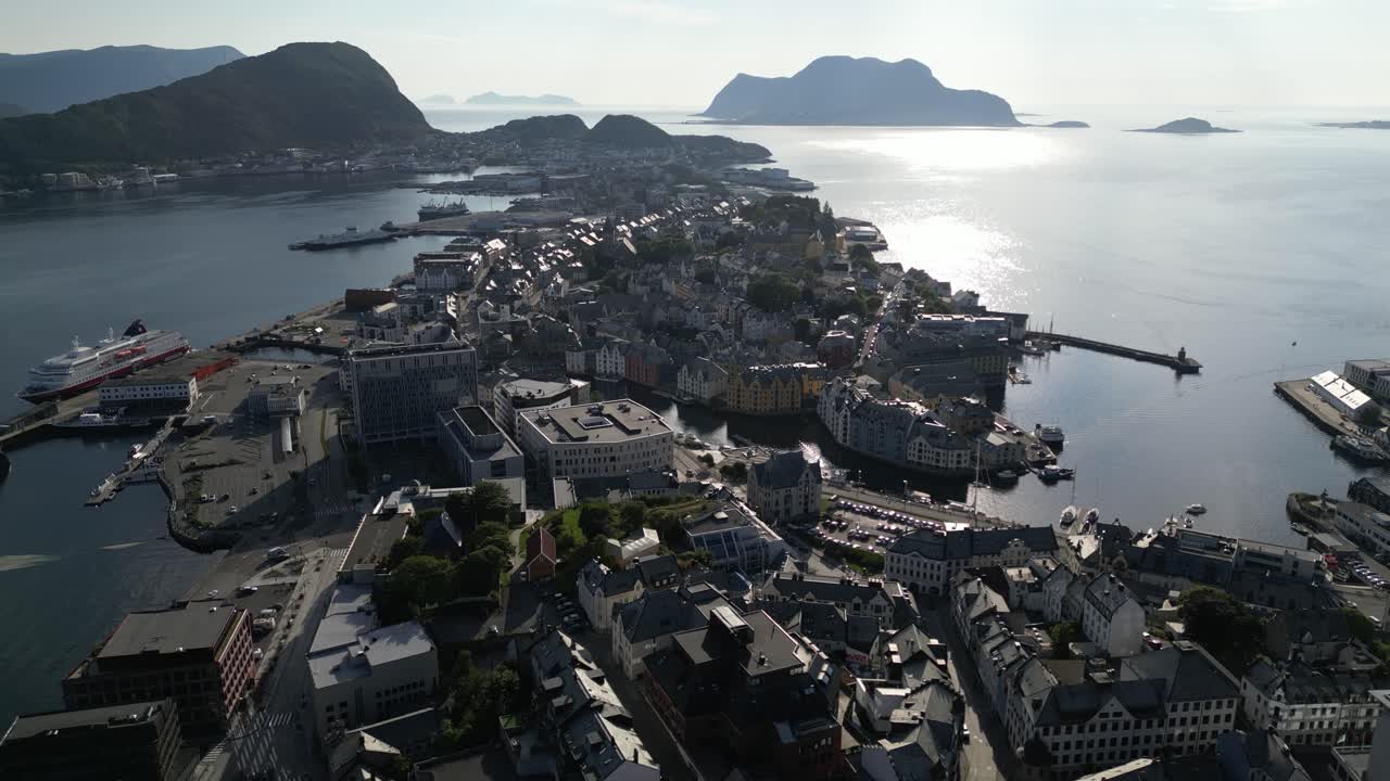 4K drone footage moving forward and slightly sideways over Ålesund city center, Norway, tilting down to reveal colorful houses, harbor, and fjord landscape under summer sunlight
