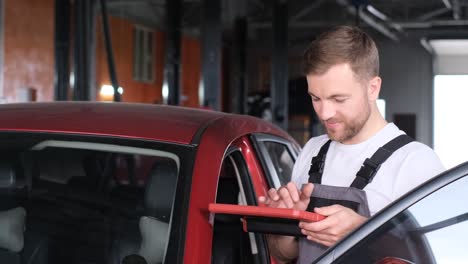 mechanic using a tablet to inspect a car in a garage