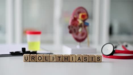 wooden blocks spelling urolithiasis with a kidney model and medical supplies