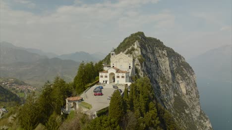 Impresionante-órbita-Aérea-De-La-Comuna-De-La-Aldea-En-La-Cima-De-La-Montaña-Que-Supervisa-El-Lago-De-Garda,-Los-Alpes-Y-El-Impresionante-Paisaje-De-Nubes