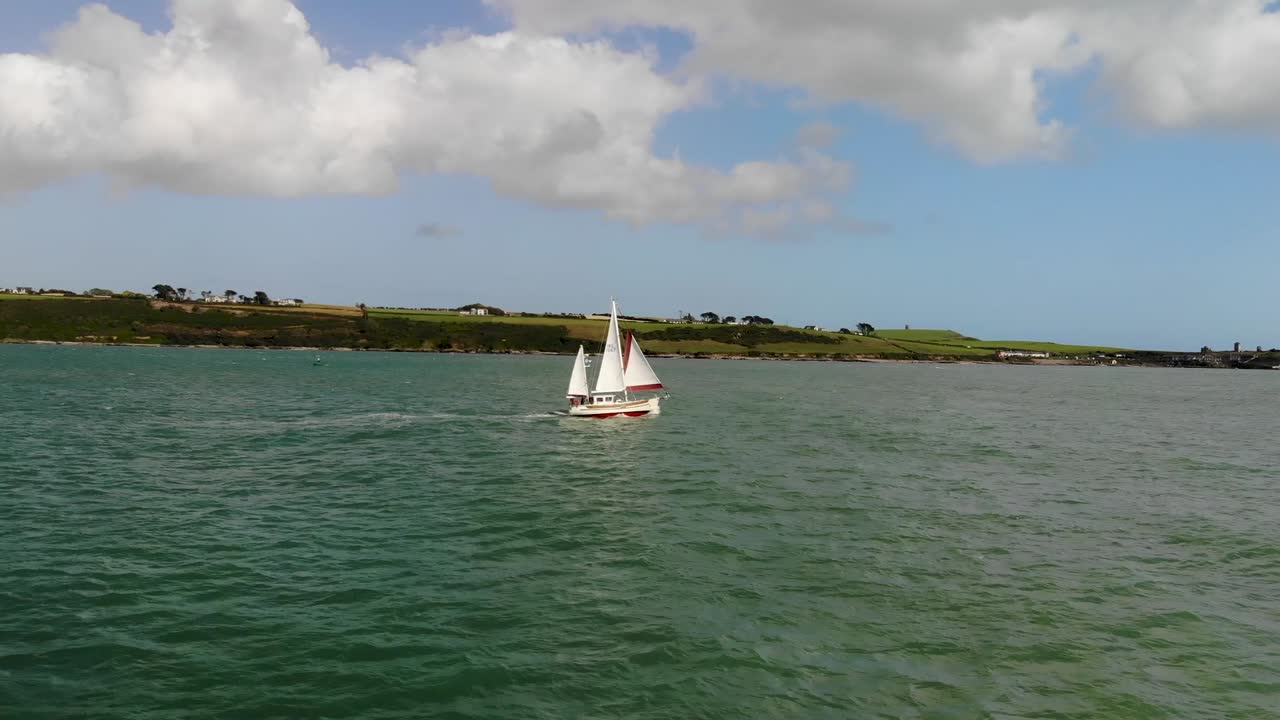 yate de vela con tres velas velas a lo largo de una costa