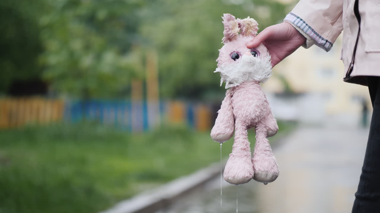 una mujer sostiene un juguete empapado en su mano, gotea agua, está lloviendo video 4k