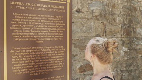 young female tourist reads foreign visitor info board cyrillic translation