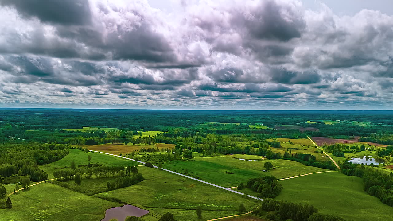 Fertile, green landscape with clouds crossing the sky and casting shadows over farmland, countryside fields and forest in rural Europe - forward aerial cloudscape hyper lapse or motion time lapse