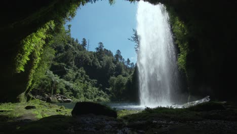 vista interior de la cueva detrás de la poderosa cascada de omanawa en nueva zelanda en un día soleado