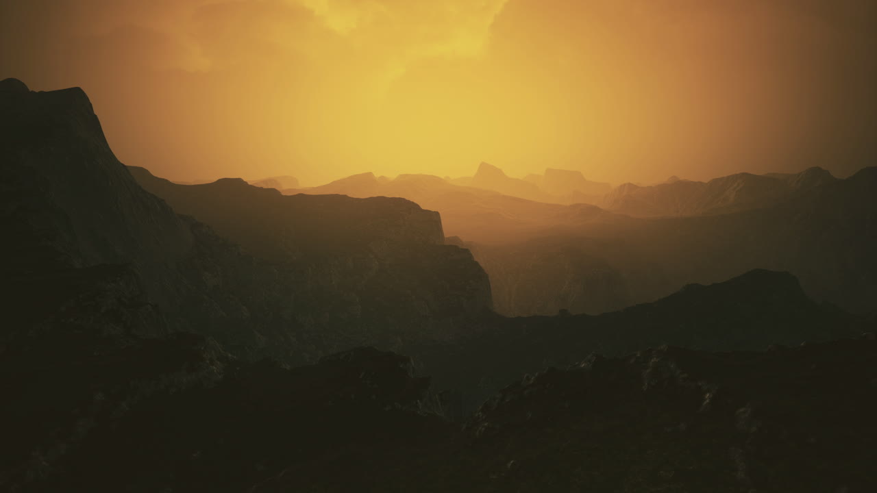 Mountain range illuminated by warm sunset hues over rugged terrain