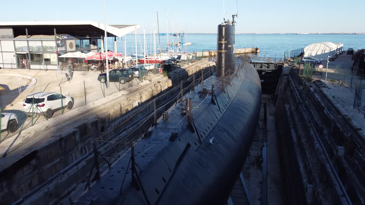 Drone shot flying over a docked submarine.