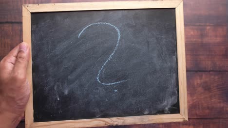 hands writing a question mark on a chalkboard