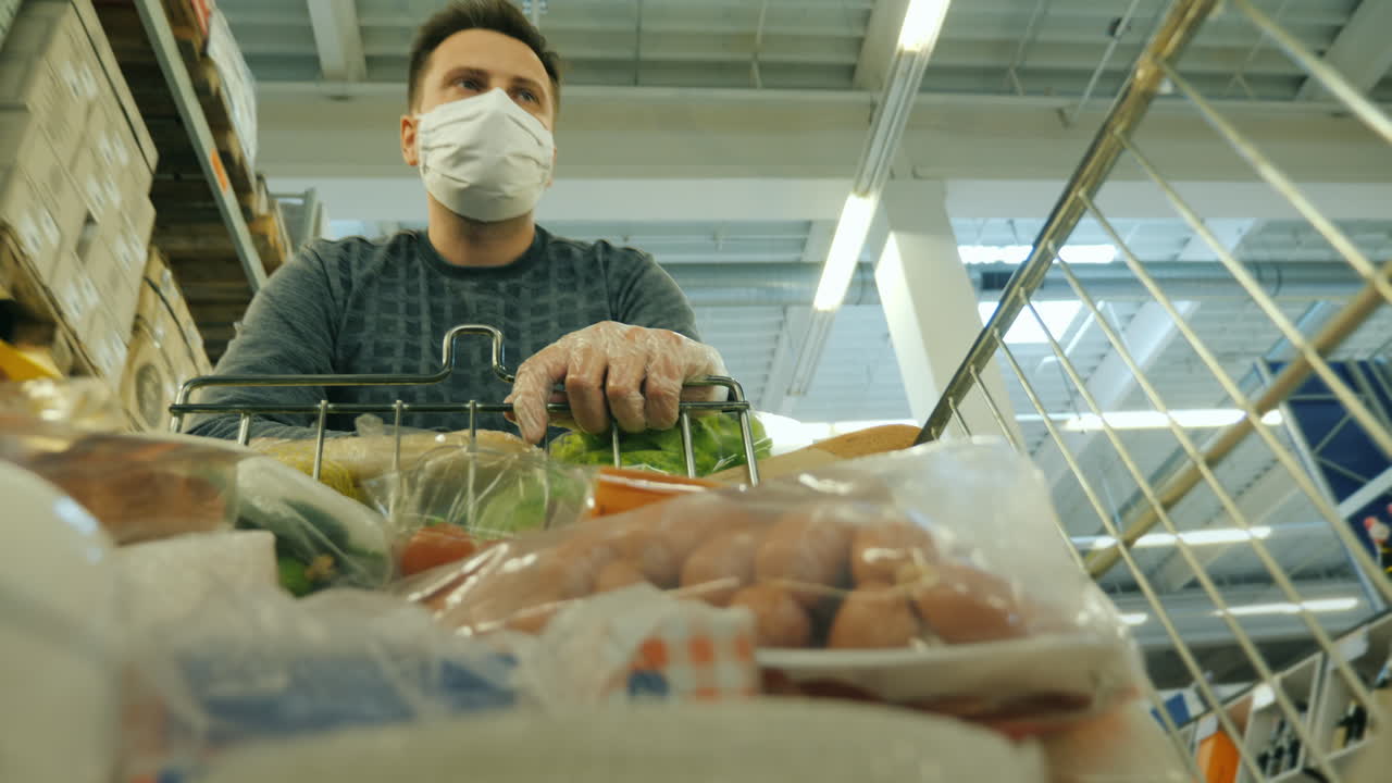 보호 마스크를 쓴 남자가 쇼핑 카트를 타고 가게를 돌아다닌다