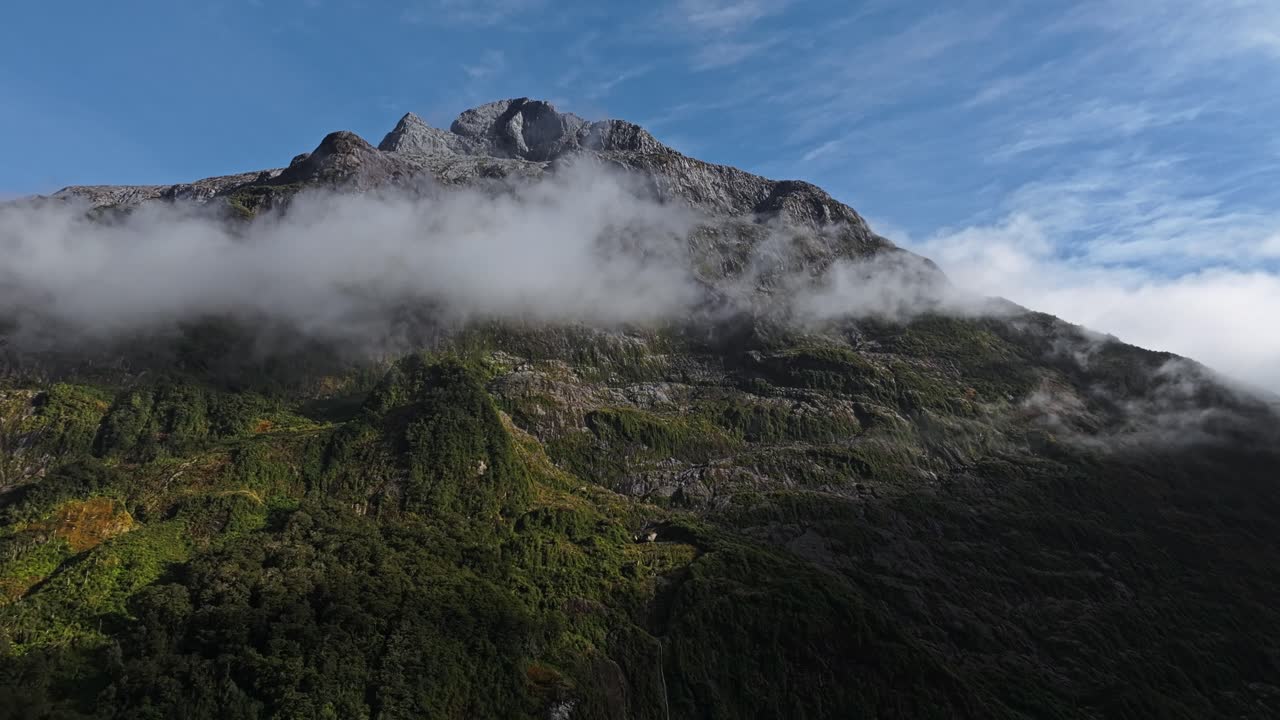la banda de nubes grises se envuelve mientras el pico estéril se expone contra el cielo azul.