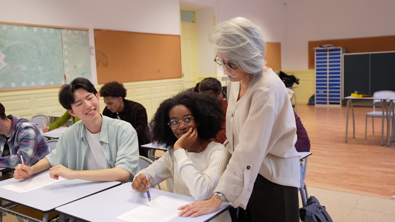 Enseignant aidant des élèves aux profils variés pendant un examen en classe