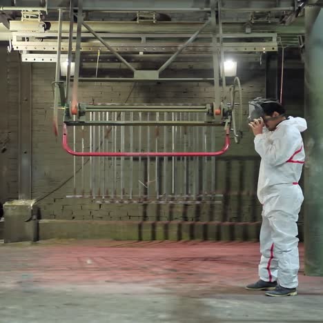 technician starts his work inside the workshop. worker in white protective suit putting on respirator on his head before the painting procedure.