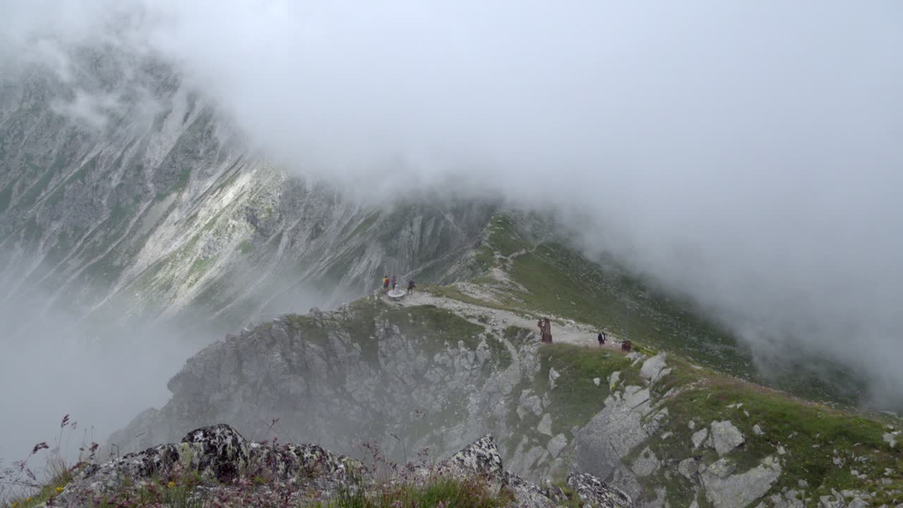 Clouds moving in on hikers just below the summit of Mount Ifinger, Sarntal Alps, South Tyrol, Italy