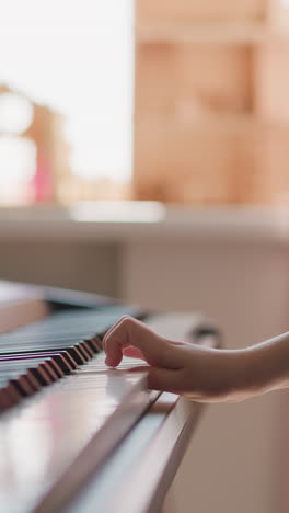 child learns to play piano standing against window in light room. girl in orthopedic corset performs melody with right hand making graceful smooth movements on blurred background