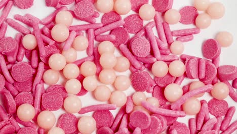 pink and peach sprinkles cascade onto a white surface, captured in extreme close-up with bright lighting