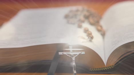 composite video of spot of light against rosary over holy bible on wooden surface