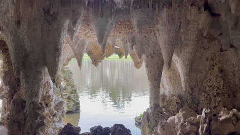 wide static shot of a man made crystal cave in the south of england, looking out on a lake