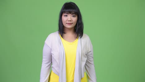 beautiful happy asian woman smiling against green background