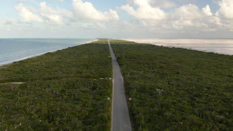 Long-straight-asphalt-road-on-isthmus-along-sea-coast-and-salt-ponds