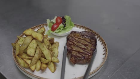 chef sirviendo bistec con gajos de patata en un plato