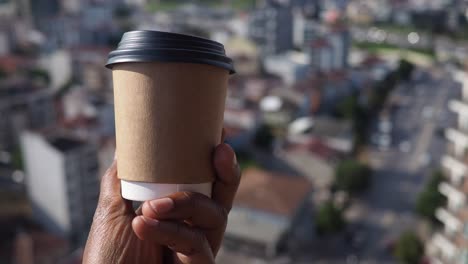 hand holding a coffee cup with a city view