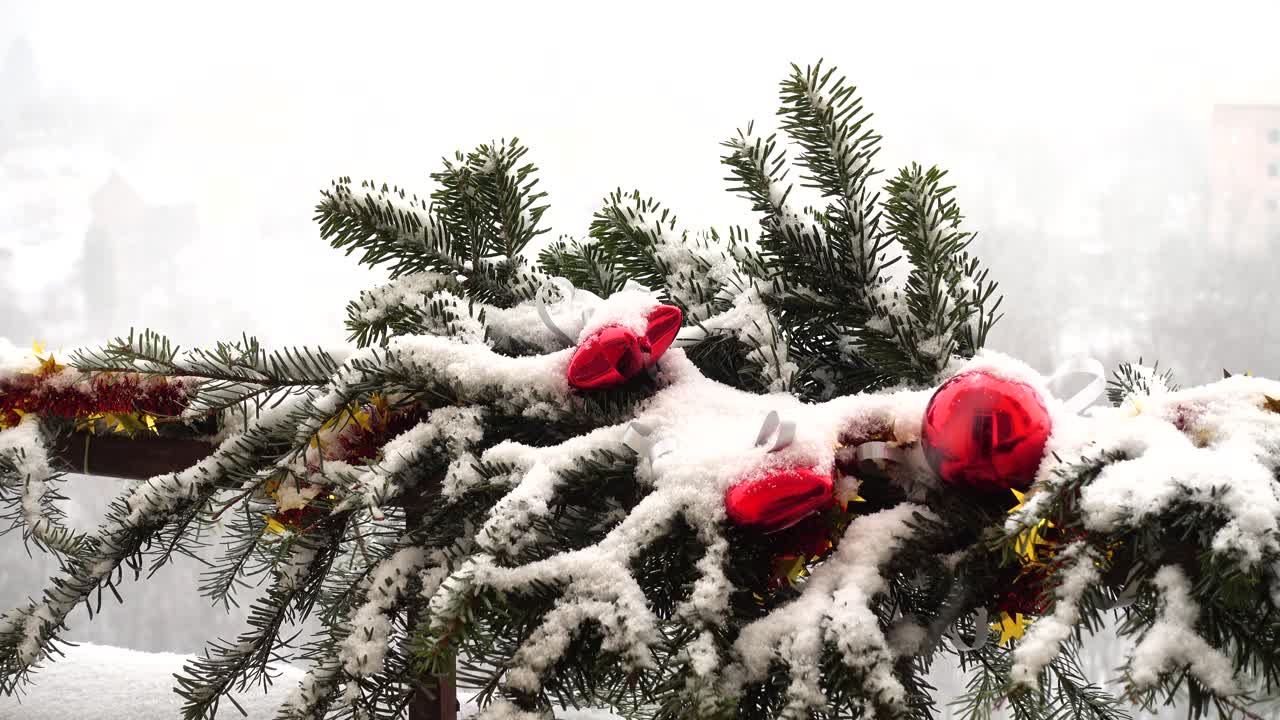 Kar altında oyuncaklarla süslenmiş yılbaşı ağacı dalları.