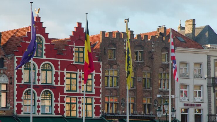 Bandiere colorate sventolano davanti agli edifici medievali a timpano nella piazza Markt di Bruges, catturate con inquadratura statica