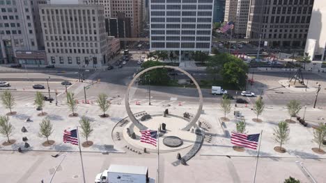 USA-flags-waving-and-Transcending-Arch-Monument-in-the-Philip-A-Hart-Plaza,-Detroit-Michigan,-USA,-aerial-view