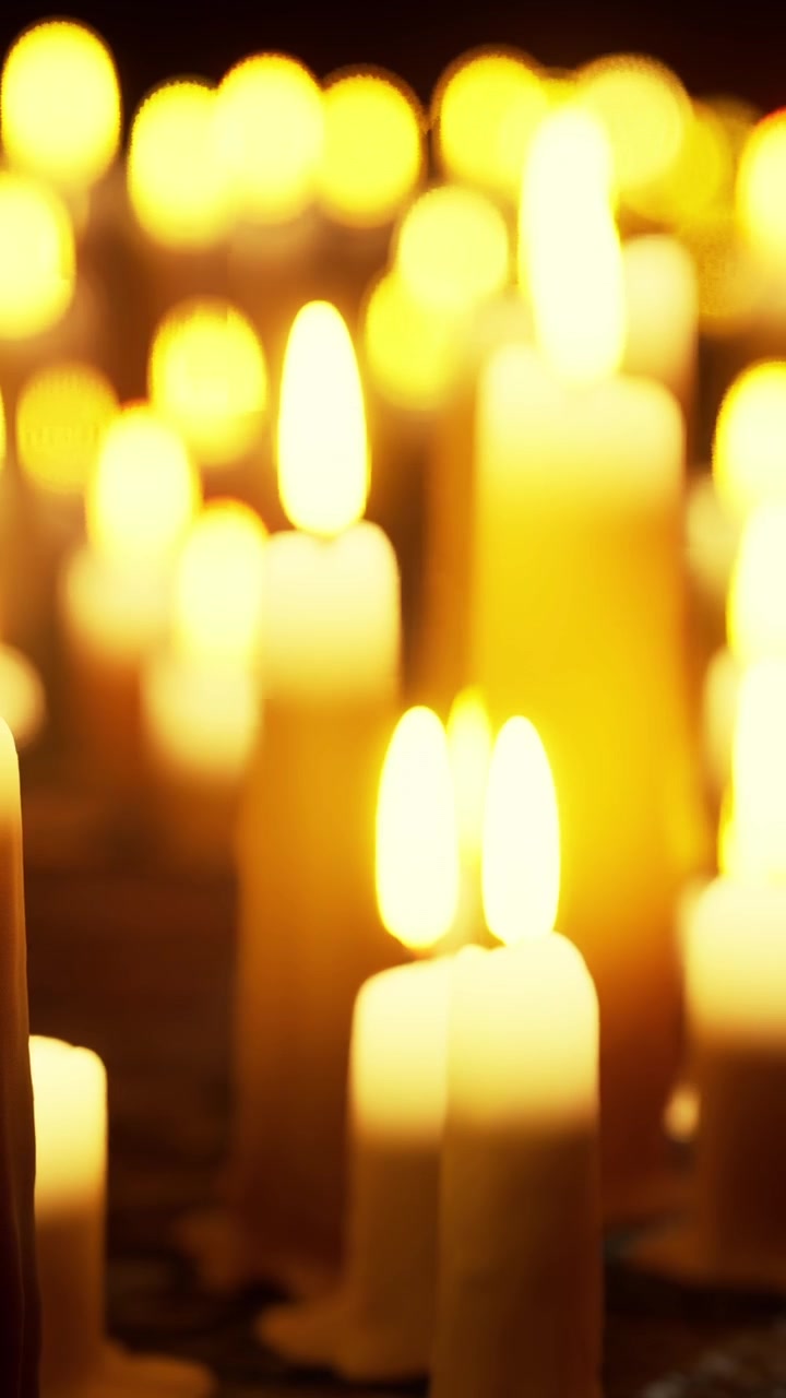 Candele illuminano uno spazio buio durante un raduno notturno.