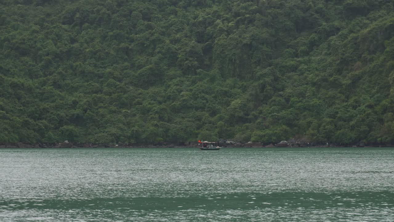 una vista de la bahía de ha long en vietnam con un barco de pesca tradicional vietnamita en la distancia