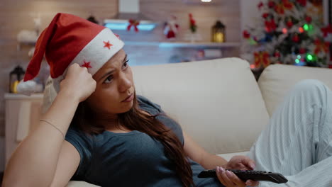 mujer cambiando de canal con el control remoto de la tv sintiéndose aburrida