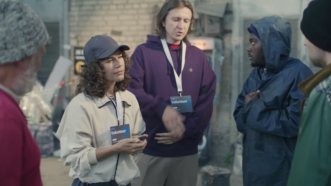 Volunteers Speaking with Group of Homeless People in Urban Alley