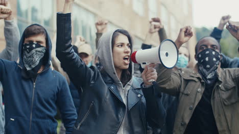 Caucasian-young-woman-in-hood-yelling-while-using-a-megaphone