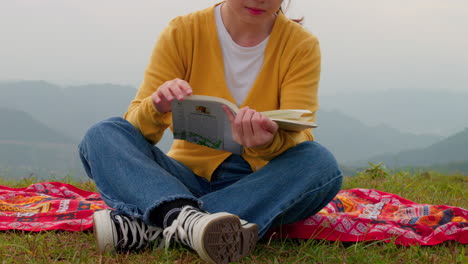 lenta revelación de una mujer leyendo un libro en una cima de una montaña ventosa