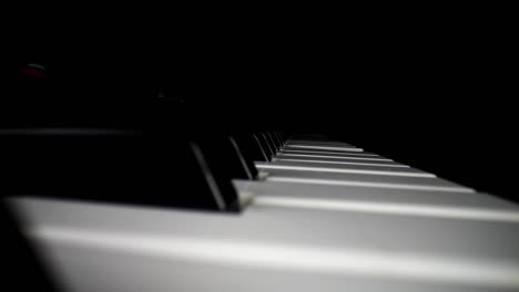 wide angle macro of electronic keyboard - static shot of keyboard and song assist lighting the keys a red color. pulling away from keys as song continues to play, keys are angled to the camera