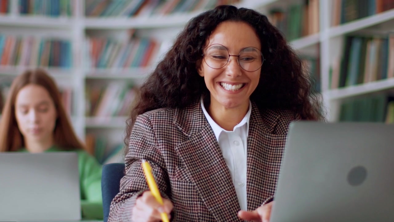 Smiling Woman Working on Laptop in Library