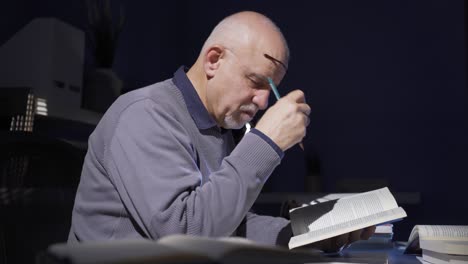 el anciano está leyendo un libro solo en su estudio.