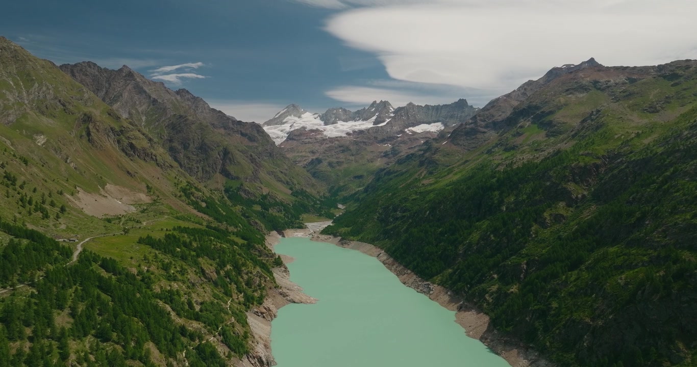 Spektakulær droneutsikt over det turkise vannet i Lago di Place Moulin, omgitt av alpine fjell og fjerne isbreer, som viser den fantastiske skjønnheten i de italienske Alpene i Aostadalen.