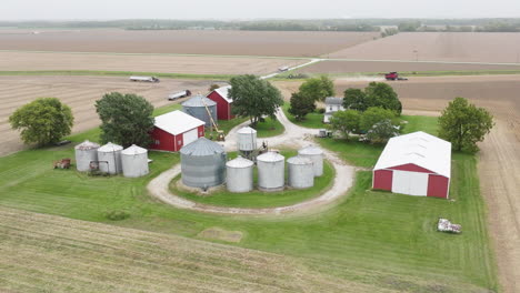 aerial view of farm with silos, barns, and harvesting machinery on expansive field