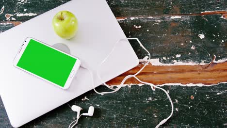 Mobile-phone-and-green-apple-on-laptop